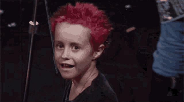 a young boy with red hair and a black shirt looks at the camera