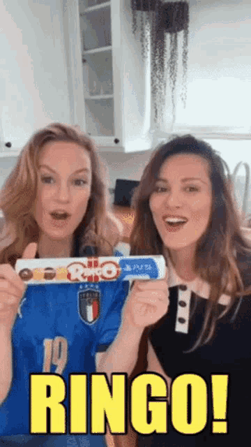 two women are holding up a bar of ringo chocolate