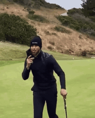 a man is holding a golf club on a green field