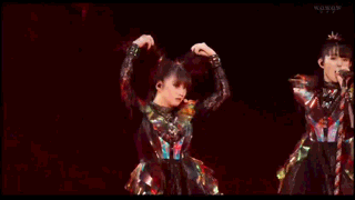 a woman in a colorful outfit is dancing on a stage in a dark room .