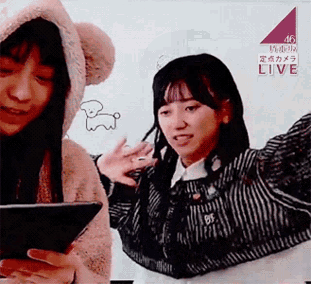 a woman in a teddy bear hood is holding a tablet in front of a sign that says live on it