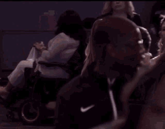 a woman in a wheelchair sits in front of a crowd wearing a shirt that says early crew