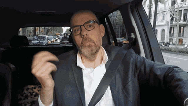 a man with glasses and a beard is in a car