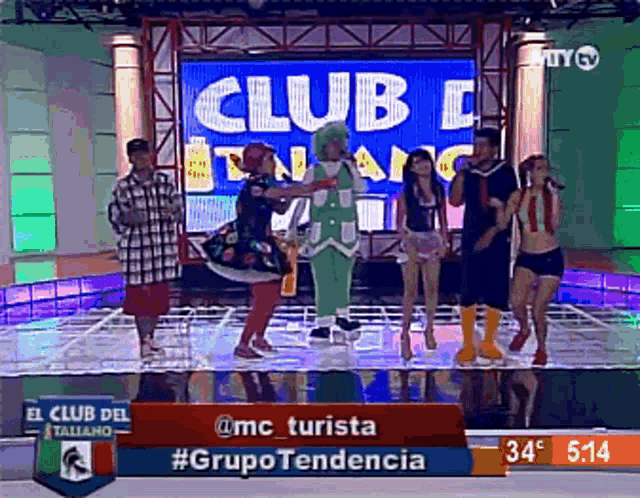 a group of people are dancing on a stage in front of a screen that says club italiano