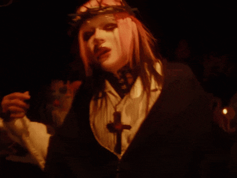 a woman with pink hair is wearing a crown of thorns