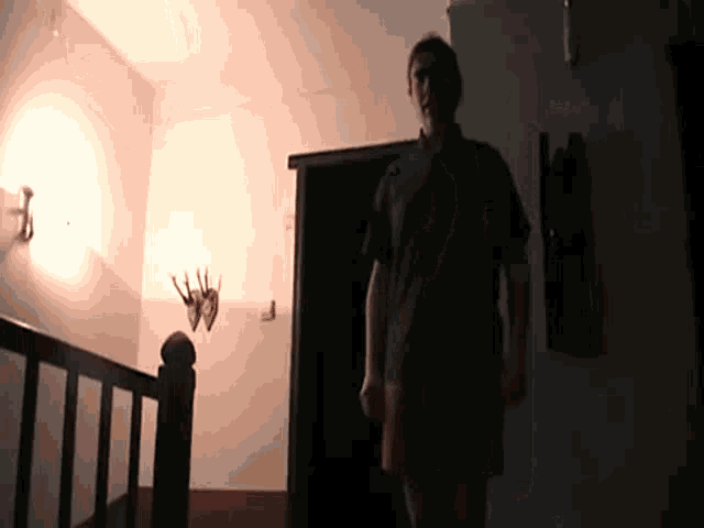 a person is standing in a dark room with a deer head on the wall