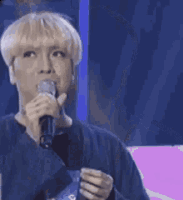 a man with blonde hair is holding a microphone in his hand .