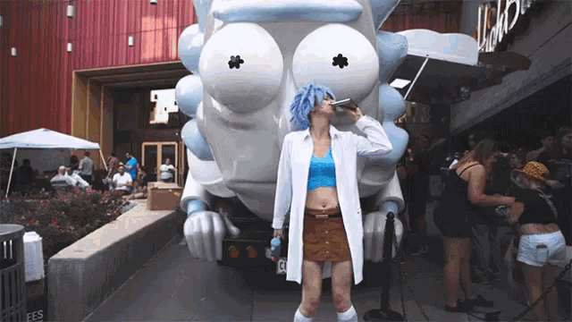 a woman stands in front of a rick and morty statue drinking from a bottle