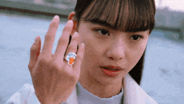 a young woman wearing a ring on her finger looks at the camera
