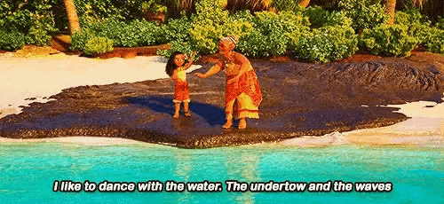 a woman and a little girl are dancing on a beach .