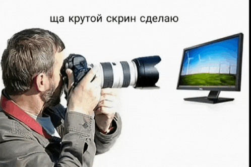 a man is taking a picture of a computer screen with russian writing on the bottom