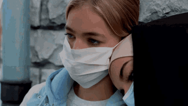 a woman wearing a face mask leans against another woman