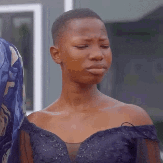 a woman in a blue off the shoulder dress is making a funny face