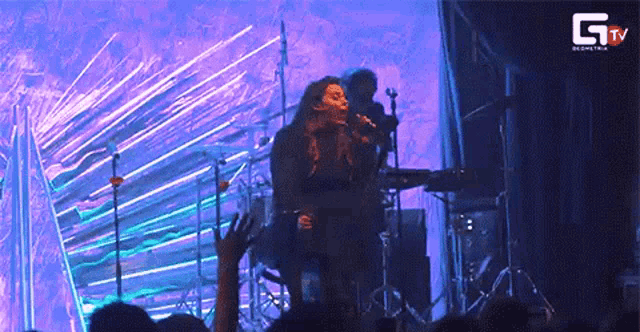 a woman singing into a microphone with gtv written on the bottom