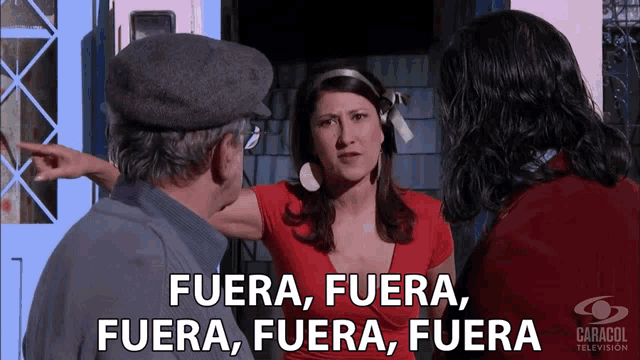 a woman in a red shirt is talking to a man and a woman with fuera fuera fuera fuera in white letters