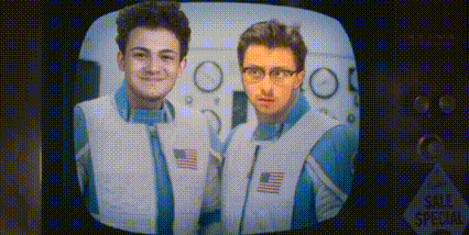 two men are standing next to each other on a tv screen .