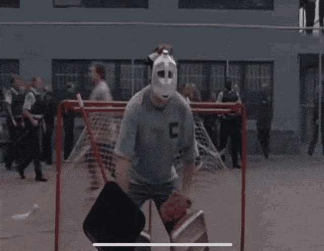 a man wearing a mask and the letter c on his shirt is playing a game of lacrosse