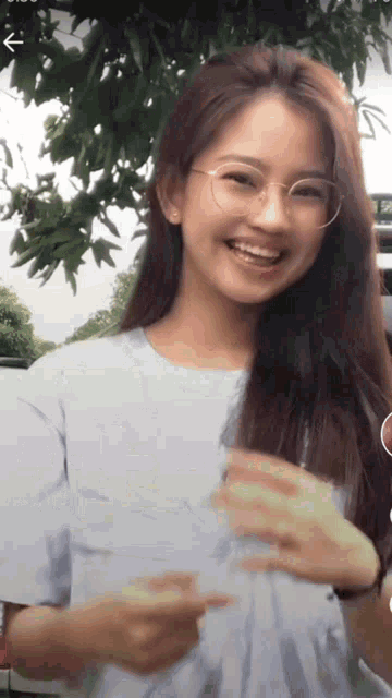 a girl wearing glasses and a white shirt smiles for the camera