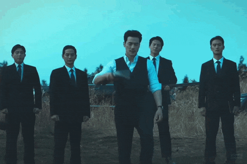 a group of men in suits and ties standing in a field with one man holding a gun