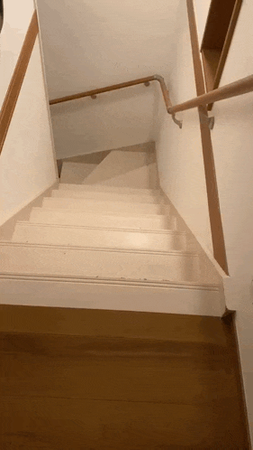 a white staircase with a wooden railing and a wooden floor