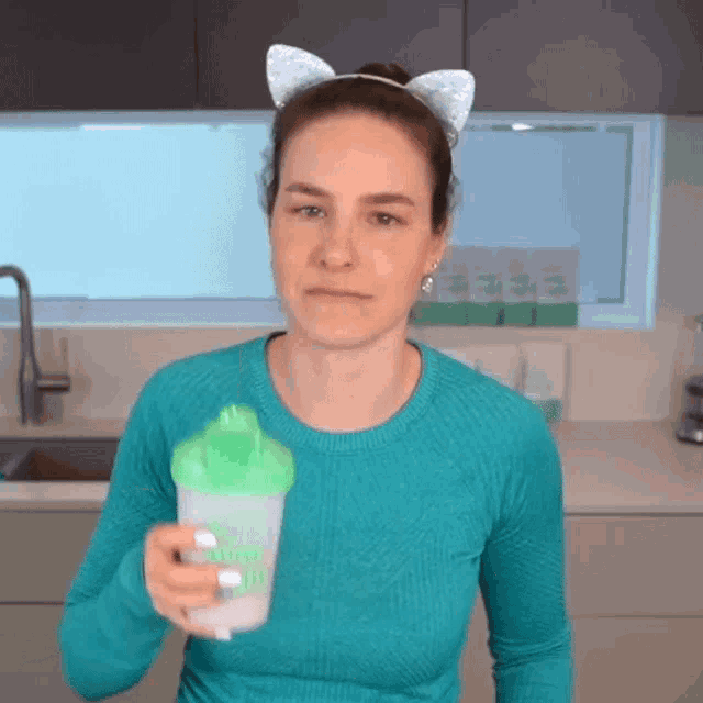a woman wearing a cat ear headband is holding a shaker that says shake up