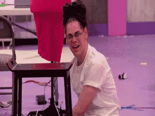 a woman wearing glasses is sitting on a stool