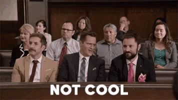 a group of men in suits and ties are sitting in a courtroom with the words `` not cool '' above them .