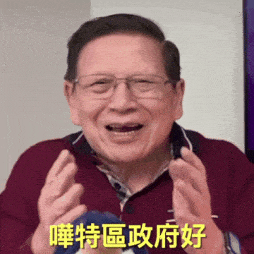 a man wearing glasses and a maroon shirt is smiling with chinese writing behind him