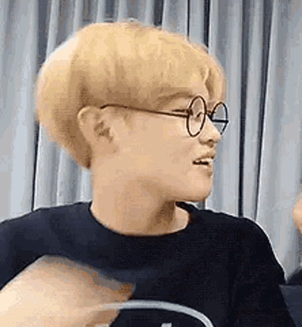 a man with blonde hair and glasses is wearing a black shirt .