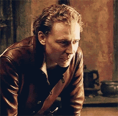 a man is wearing a brown leather jacket and looking down .