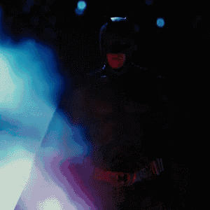 a man in a batman costume is standing in a dark room surrounded by blue smoke