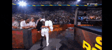 a wrestling match is being shown on peacock and a crowd is watching .