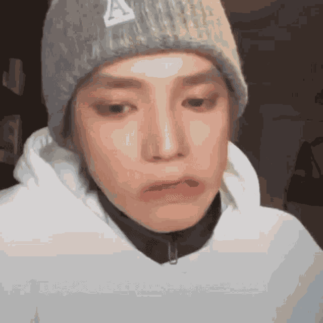 a close up of a person wearing a beanie and a hoodie .