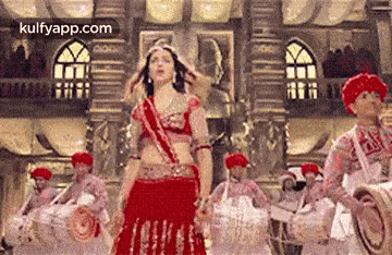 a woman in a red dress is dancing in front of a group of men .