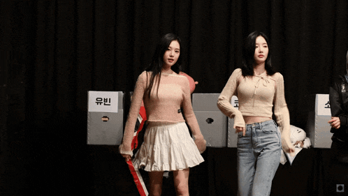 two girls are dancing in front of a sign that says ' 코토 ' on it
