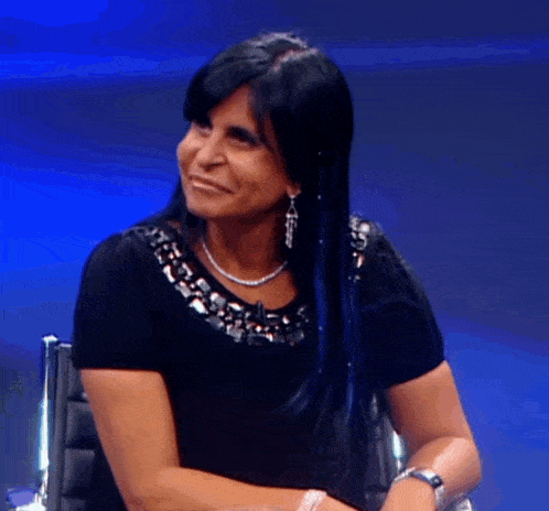 a woman with long black hair and a necklace smiles