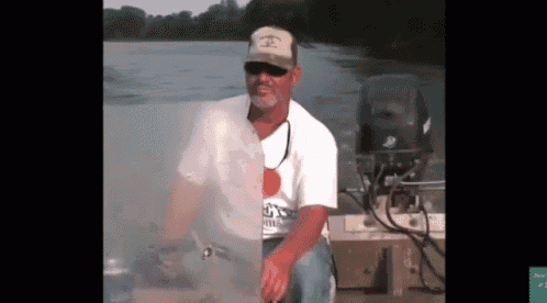 a man in a hat and sunglasses is sitting on a boat