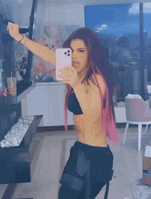 a woman with pink hair is taking a picture of herself