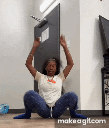 a woman squatting on the floor with her arms in the air and a make a gif.com logo in the corner
