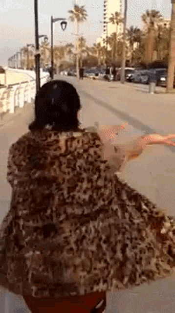 a woman in a leopard print dress is walking down a street