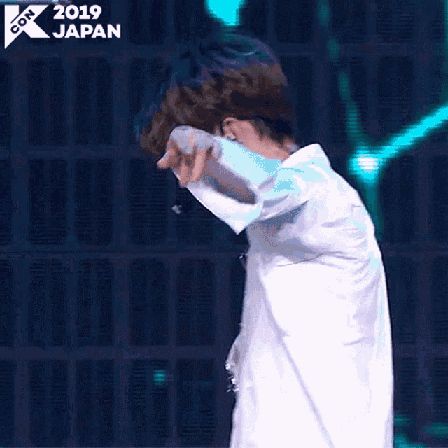 a man in a white shirt is dancing on a stage in front of a wall .