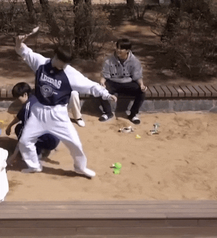 a group of people are playing in a sandbox and one of them is wearing a adidas shirt .