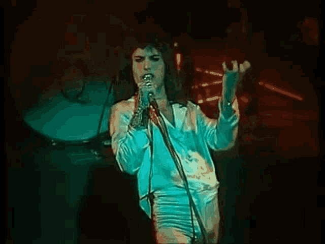 a woman is singing into a microphone on a stage in front of a crowd .