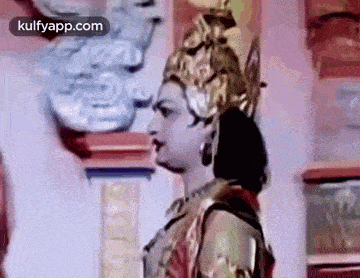 a woman is wearing a crown and earrings and standing in front of a wall .