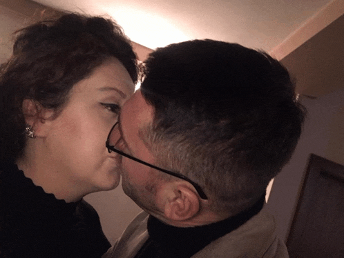 a man and a woman kissing with the woman wearing glasses