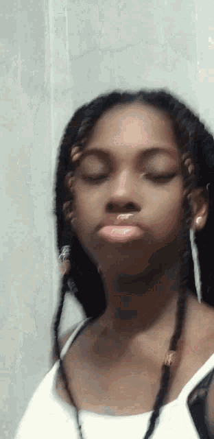 a young girl with braids and earrings is making a funny face .