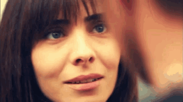 a close up of a woman 's face with a man behind her