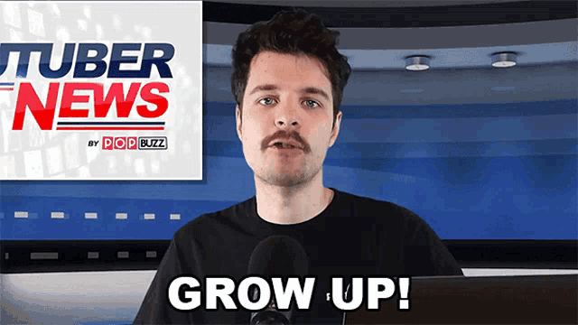 a man with a mustache is talking into a microphone in front of a tuber news sign
