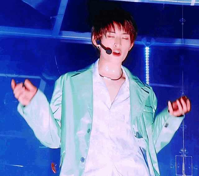 a man wearing a green jacket and a microphone on his neck
