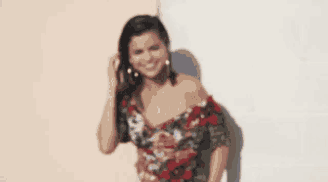 a woman is wearing a floral off the shoulder top and hoop earrings .